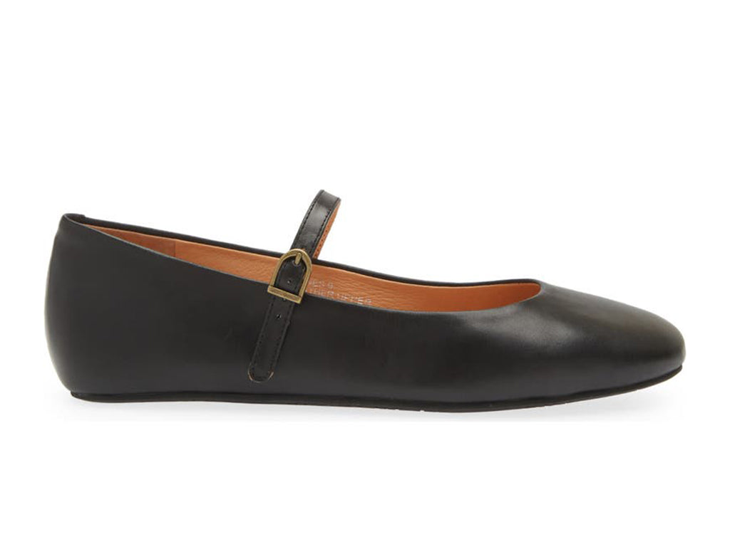 Black leather rounded toe flat with over the instep buckle strap on a white background side view
