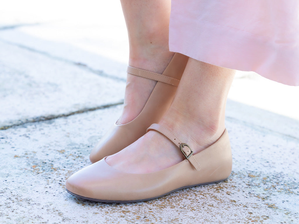 Sand leather rounded toe flat with over the instep buckle strap on a white background side angle view