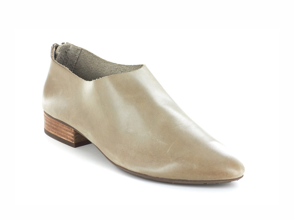Taupe leather pointed toe flat with mini block heel and back zipper on a white background side angle view