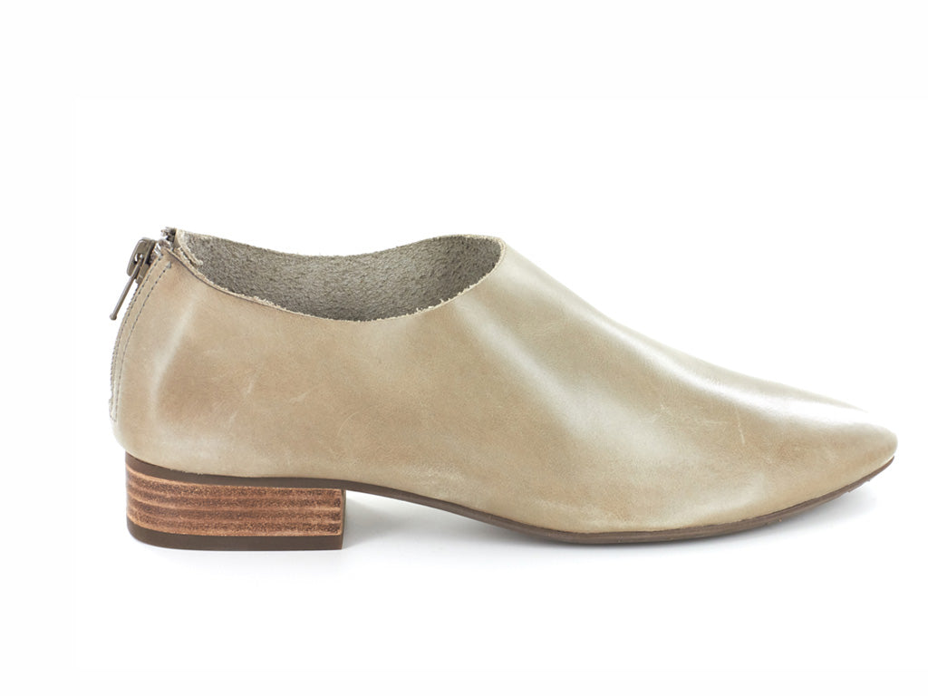 Taupe leather pointed toe flat with mini block heel and back zipper on a white background side view