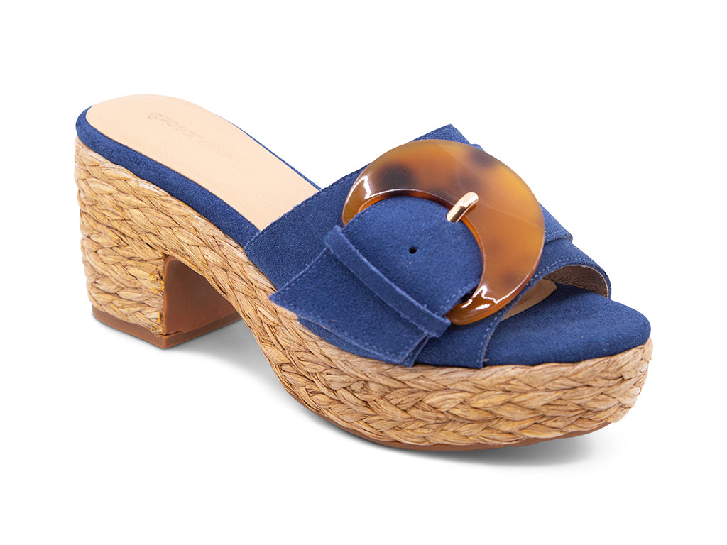 blue suede sandal with a moon shaped buckle on a raffia wrapped platform