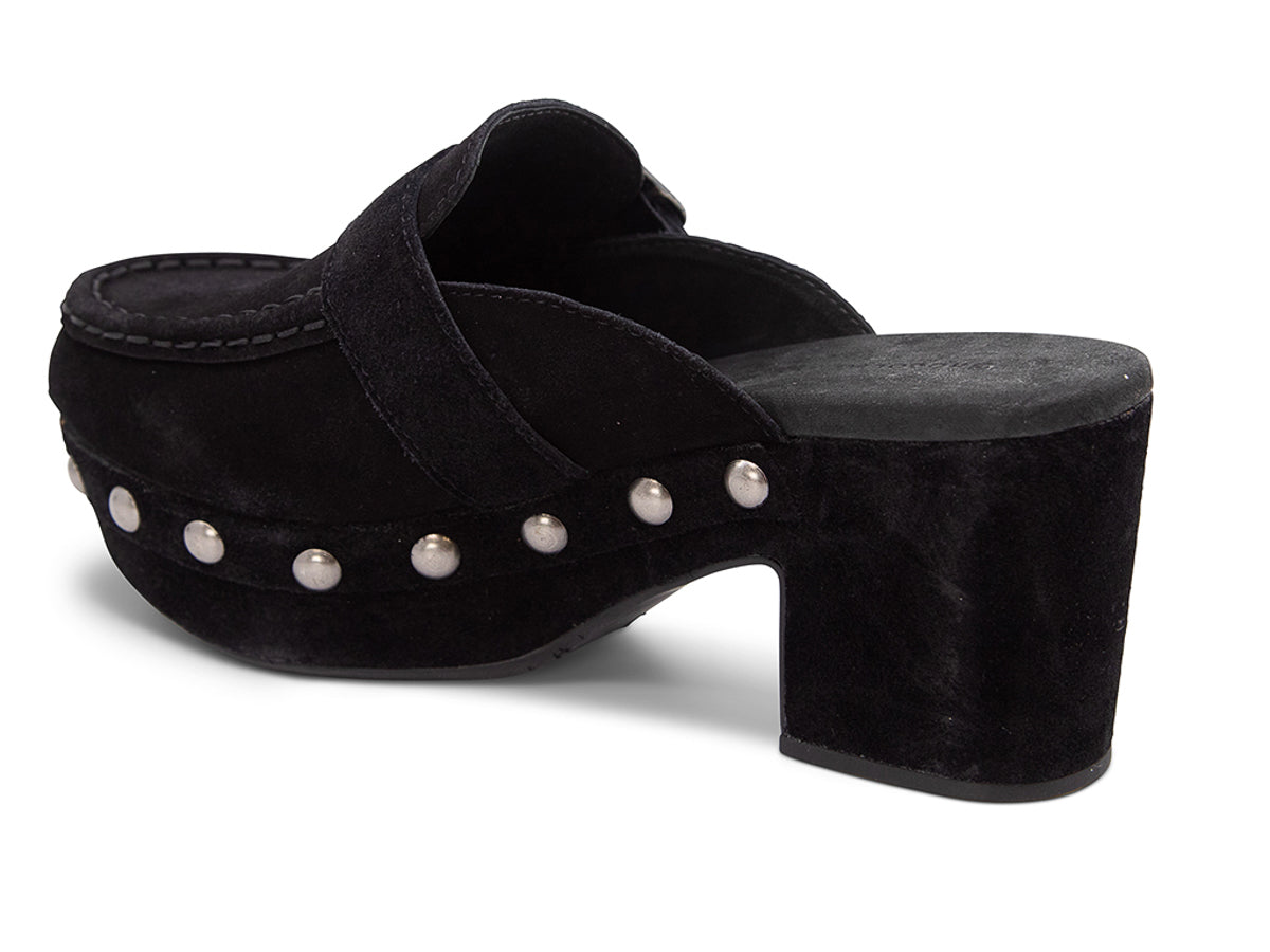 Black suede slide in block heel clog shoe with a decorative strap buckle and grommet studson a white background side angle view 