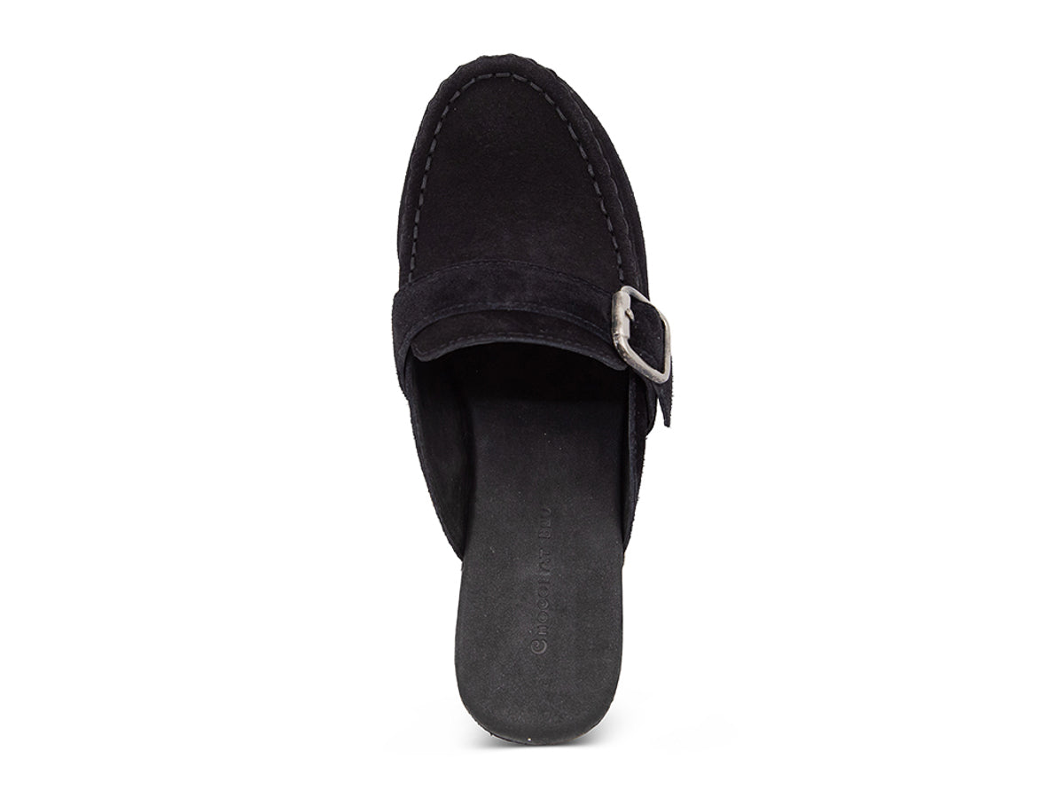 Black suede slide in block heel clog shoe with a decorative strap buckle and grommet studson a white background top view 