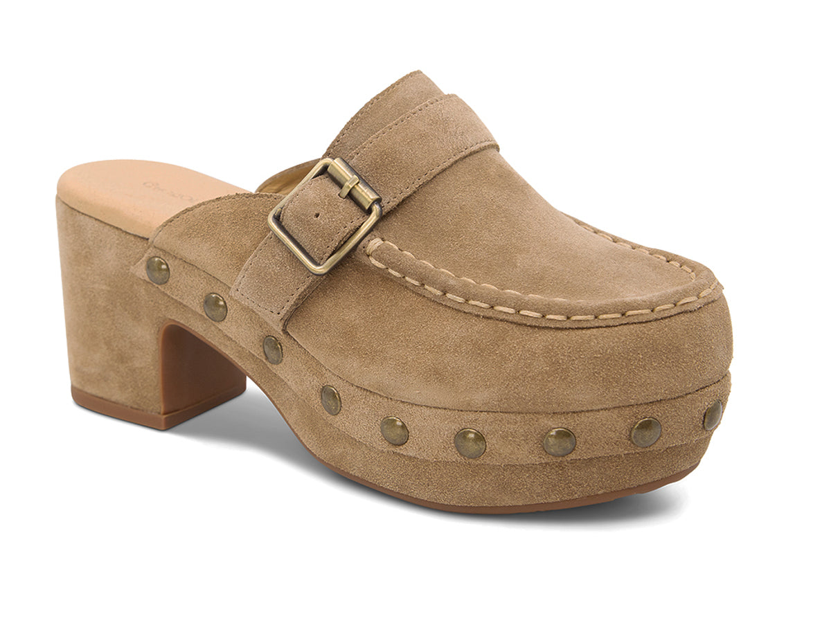 Camel suede slide in block heel clog shoe with a decorative strap buckle and grommet studson a white background side angle view 