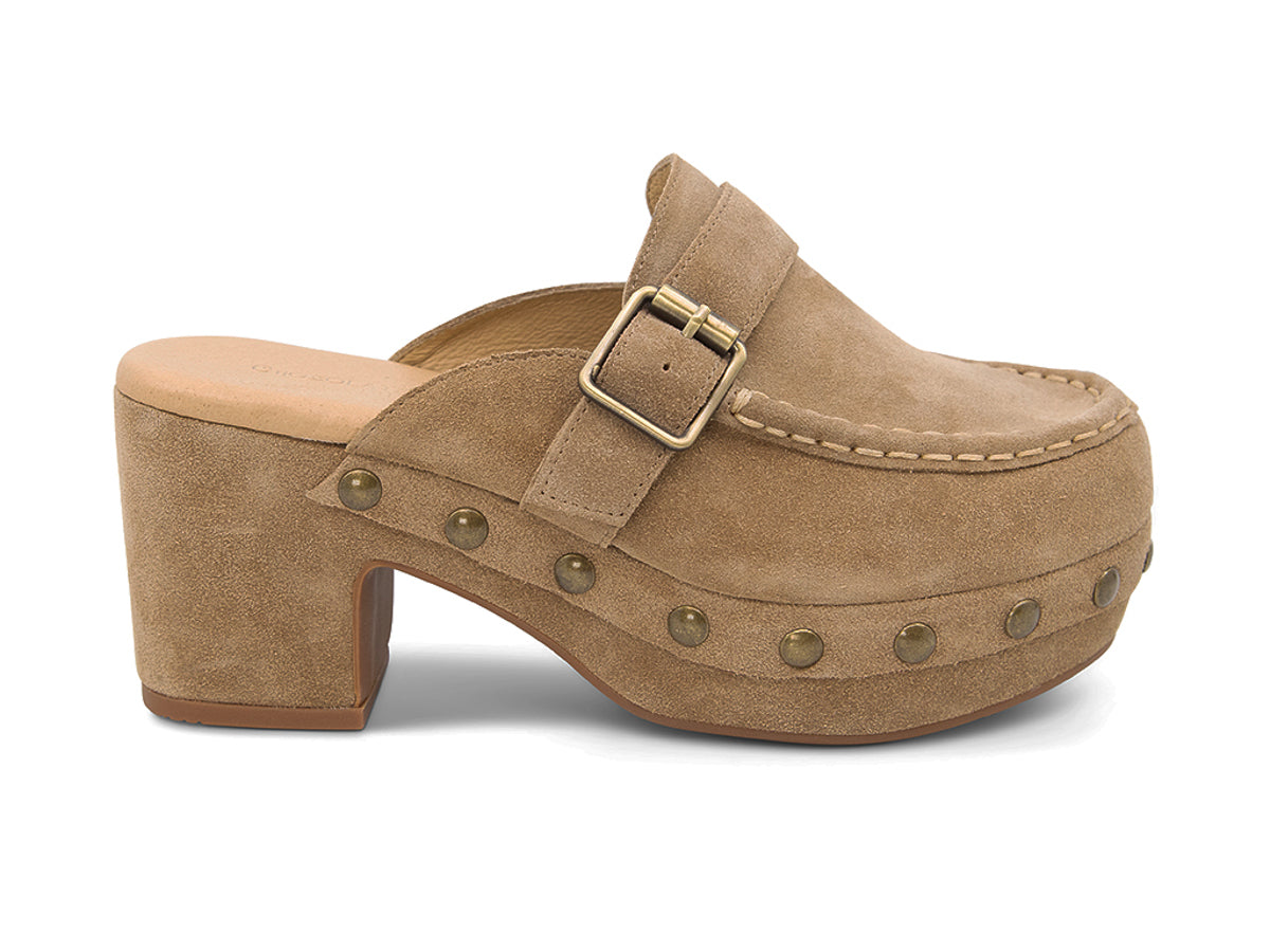Camel suede slide in block heel clog shoe with a decorative strap buckle and grommet studson a white background side view 