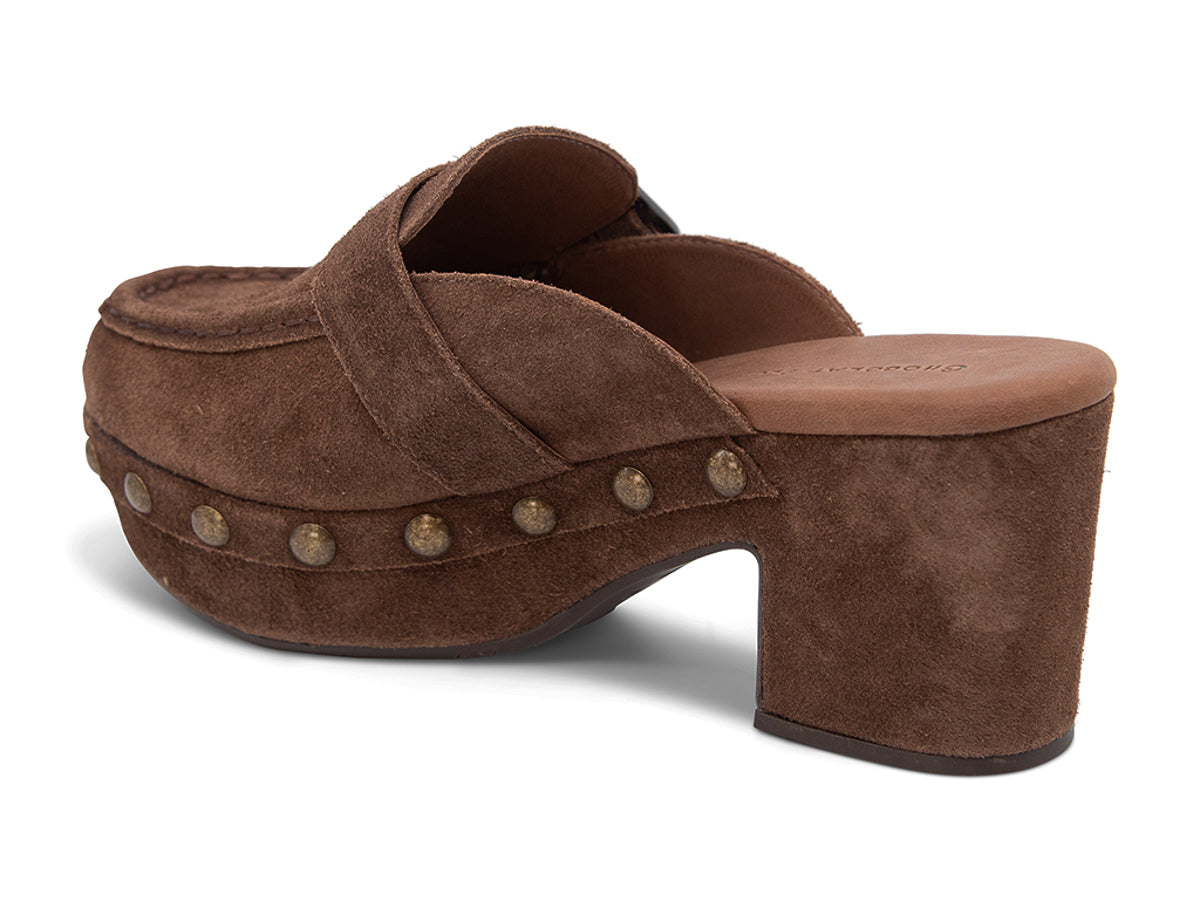 Chocolate suede slide in block heel clog shoe with a decorative strap buckle and grommet studson a white background side angle view 