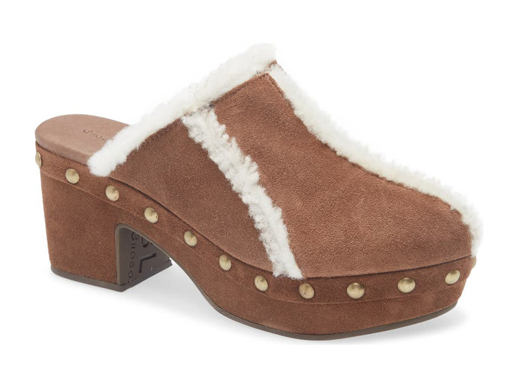 Brown suede platform heeled clog with white fur lining and gold studs on a white background side angle view
