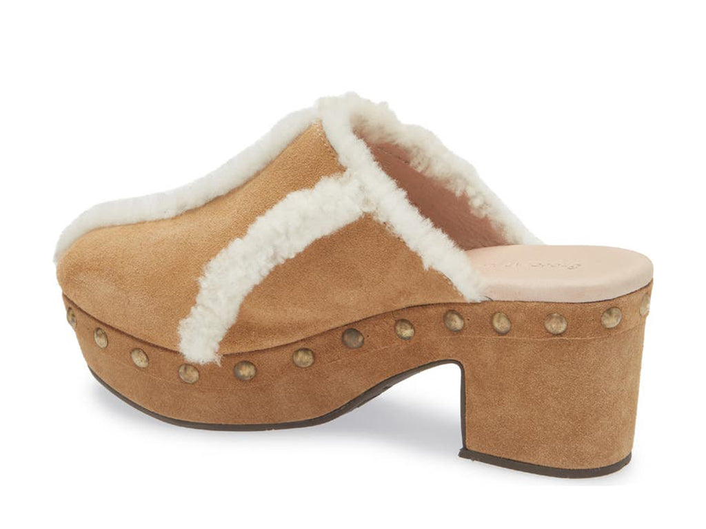 Tan suede platform heeled clog with white fur lining and gold studs on a white background side angle view