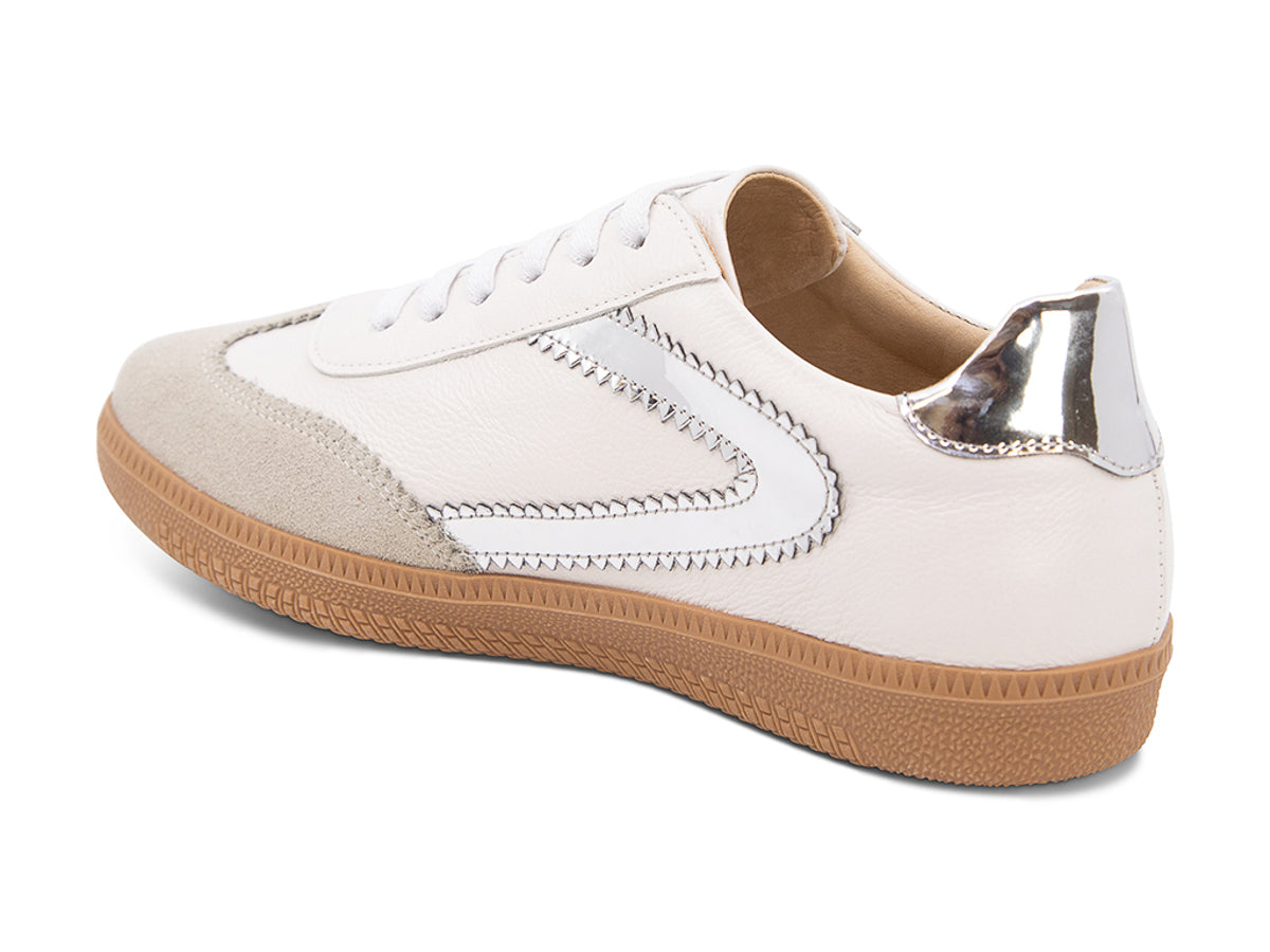 White sneaker with brown sole and silver decorative design on a white background side angle view