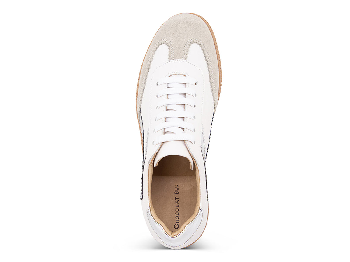 White sneaker with brown sole and silver decorative design on a white background top view