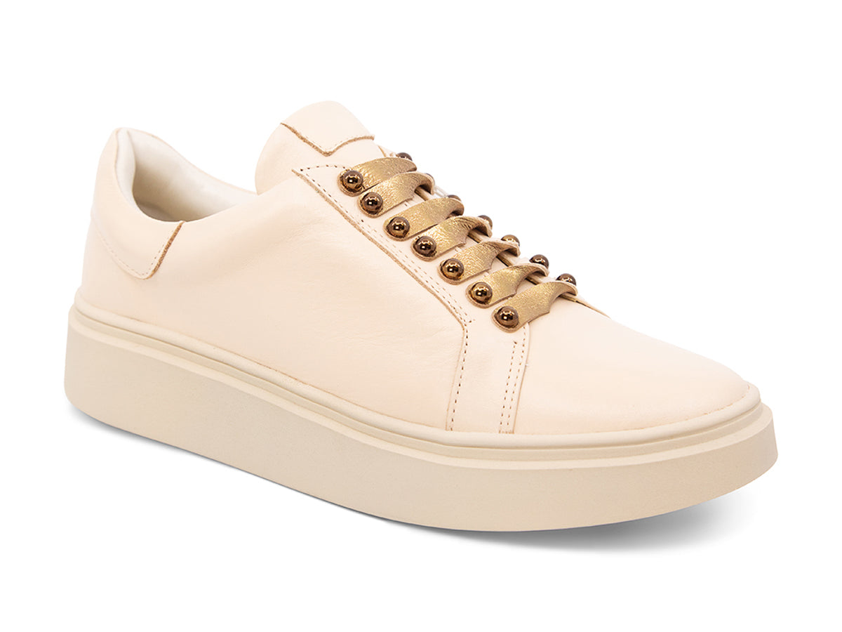 Beige sneaker with gold laces and studs on laces on a white background side angle view