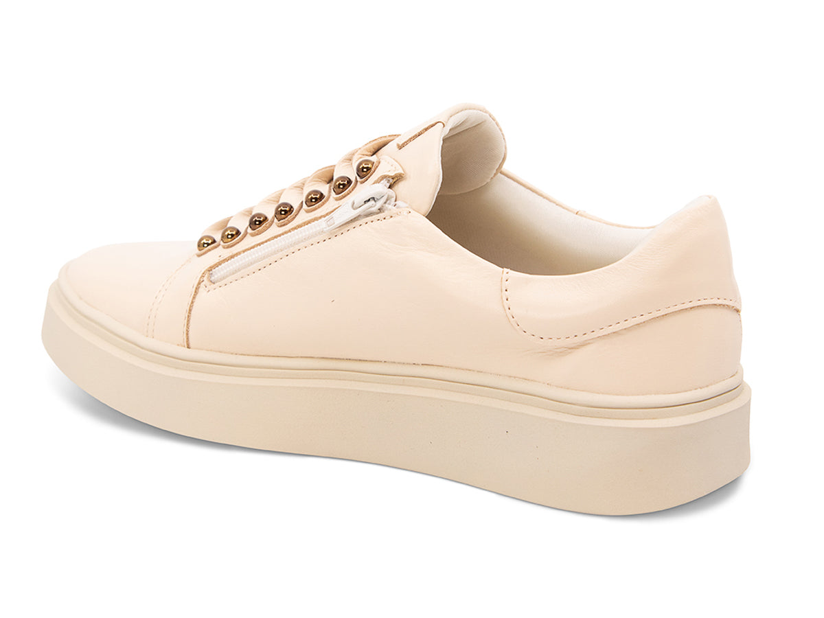 Beige sneaker with gold laces and studs on laces on a white background side angle view