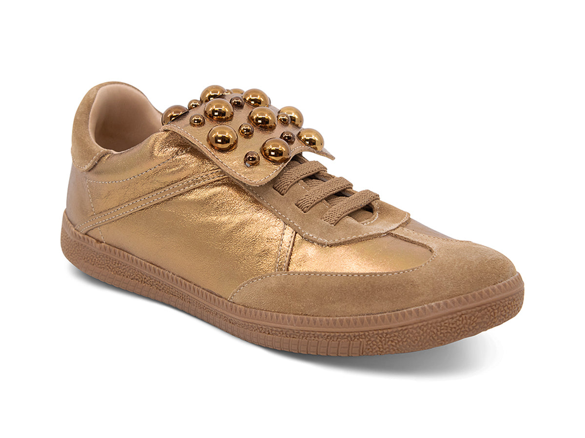 Gold and brown sneaker with decorative stud embellishments and brown sole on a white background side angle view