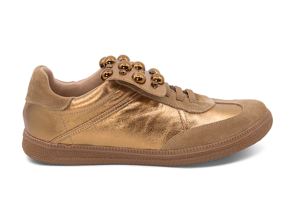 Gold and brown sneaker with decorative stud embellishments and brown sole on a white background side view