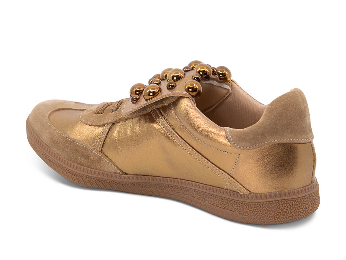 Gold and brown sneaker with decorative stud embellishments and brown sole on a white background side angle view