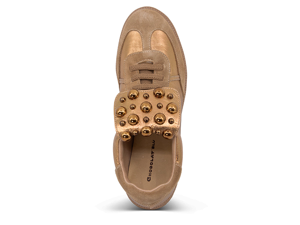 Gold and brown sneaker with decorative stud embellishments and brown sole on a white background top view