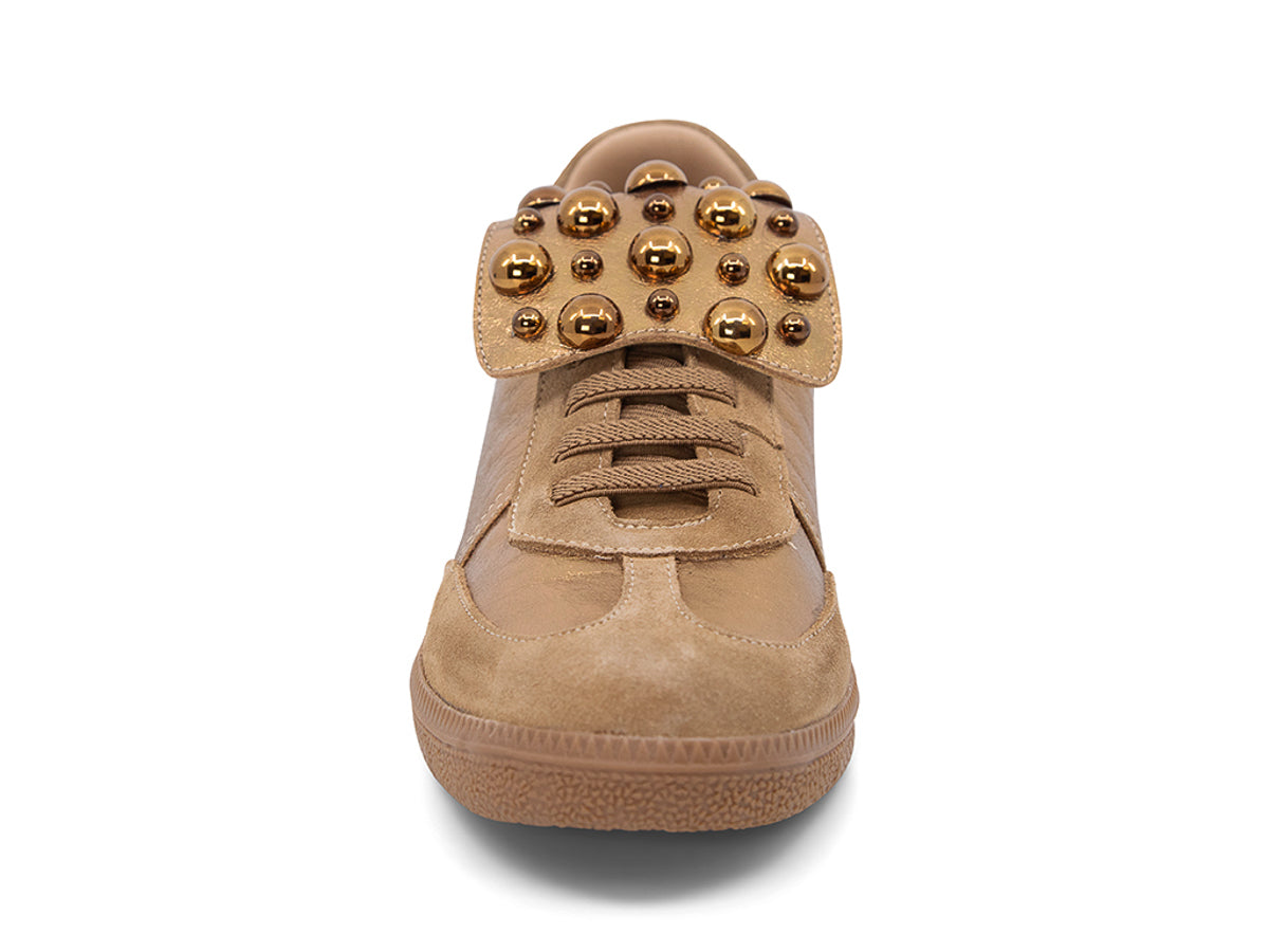 Gold and brown sneaker with decorative stud embellishments and brown sole on a white background front view