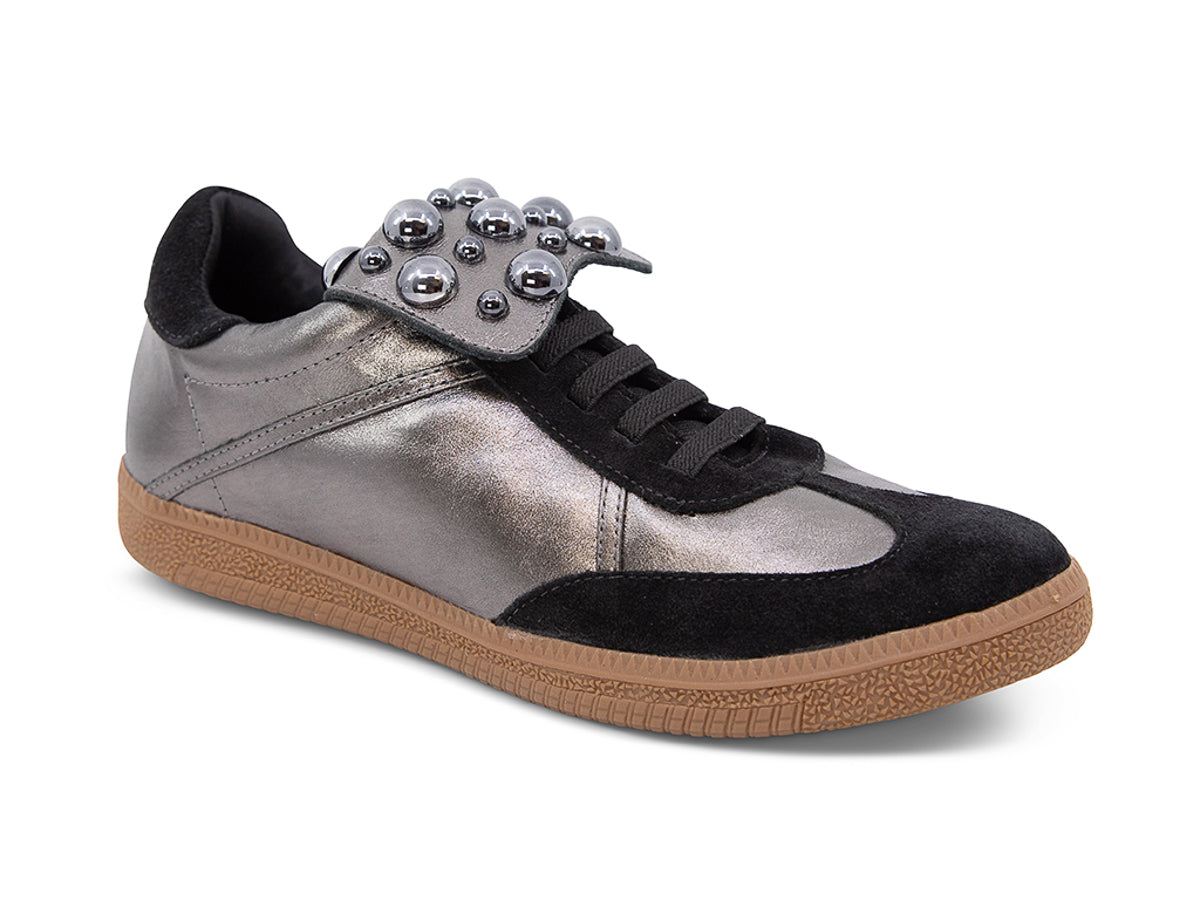 Silver and black sneaker with decorative stud embellishments and brown sole on a white background side angle view