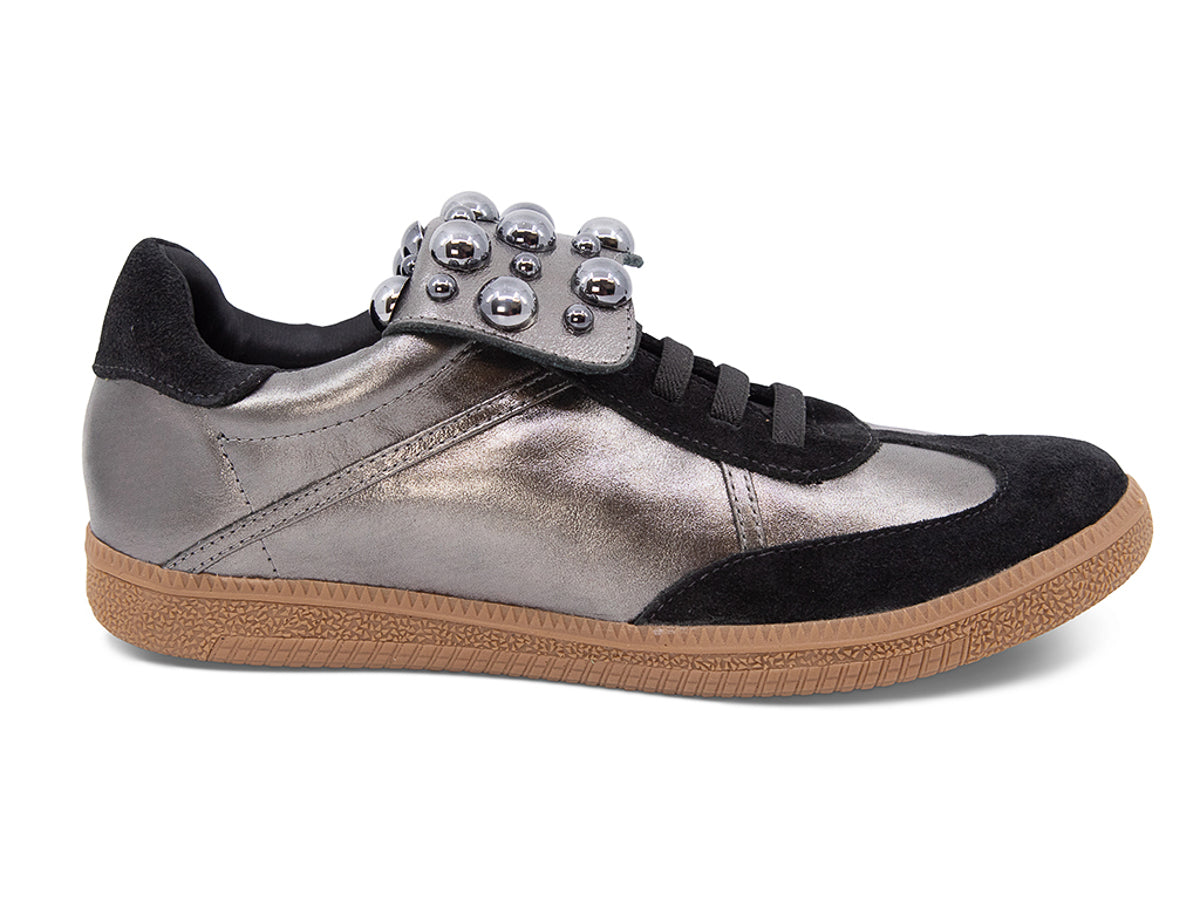 Silver and black sneaker with decorative stud embellishments and brown sole on a white background side view