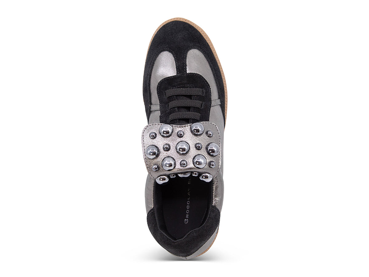 Silver and black sneaker with decorative stud embellishments and brown sole on a white background top view