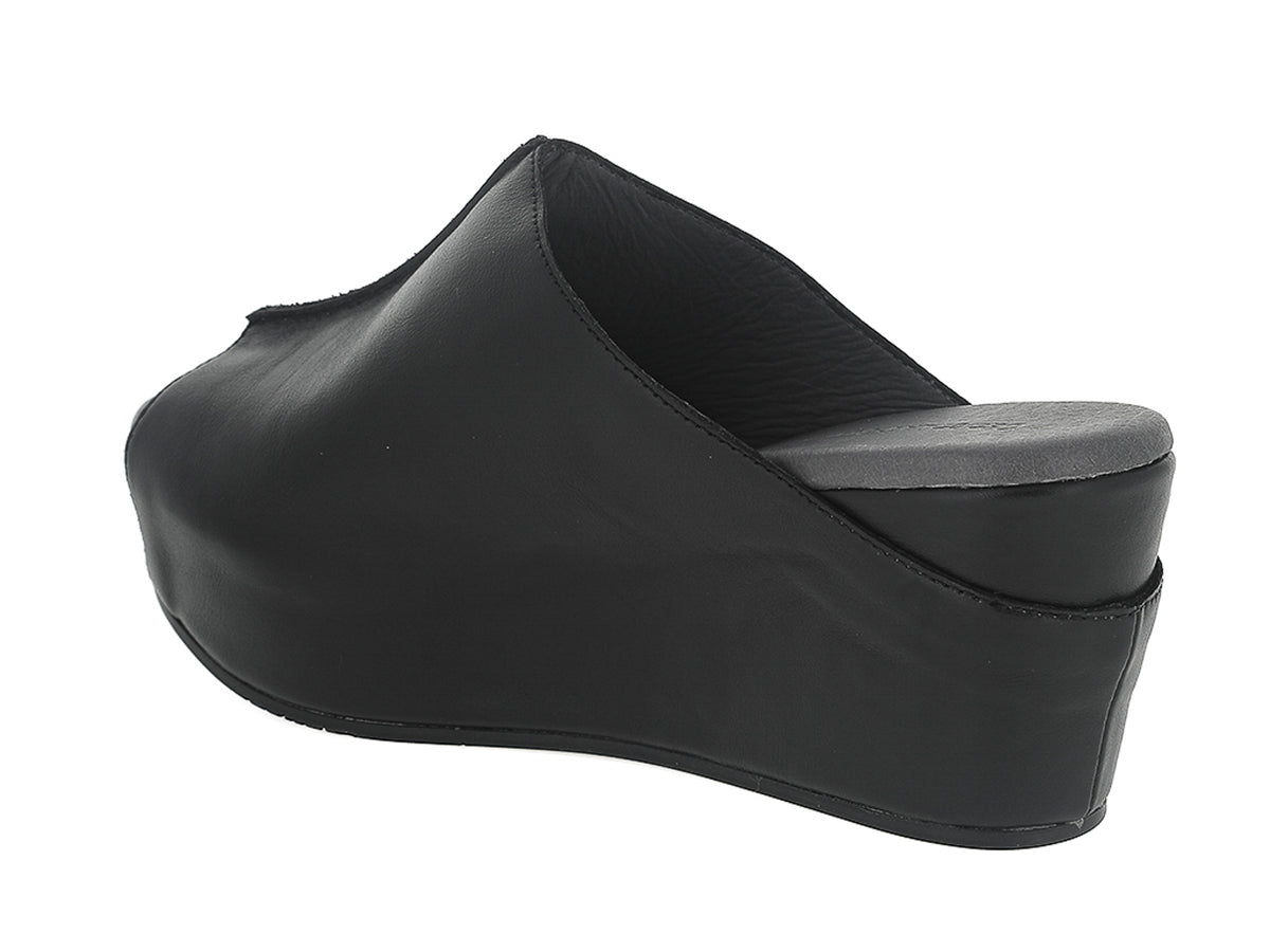 Black leather slide in peep toe wedge platform shoe with exposed seam on upper design on a white background side angle view