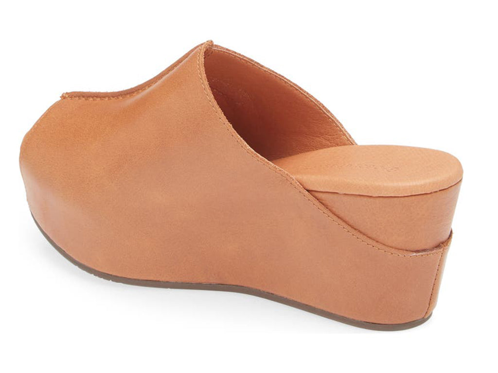 Cognac leather slide in peep toe wedge platform shoe with exposed seam on upper design on a white background side angle view
