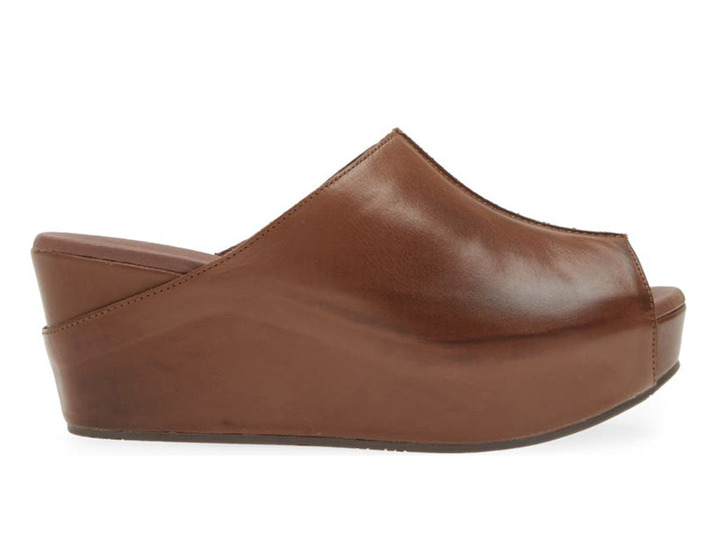 Dark brown leather slide in peep toe wedge platform shoe with exposed seam on upper design on a white background side view