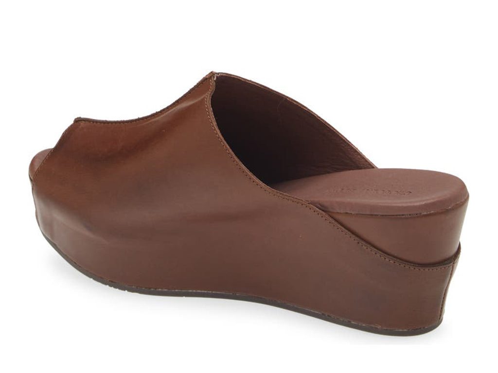 Dark brown leather  slide in peep toe wedge platform shoe with exposed seam on upper design on a white background side angle view