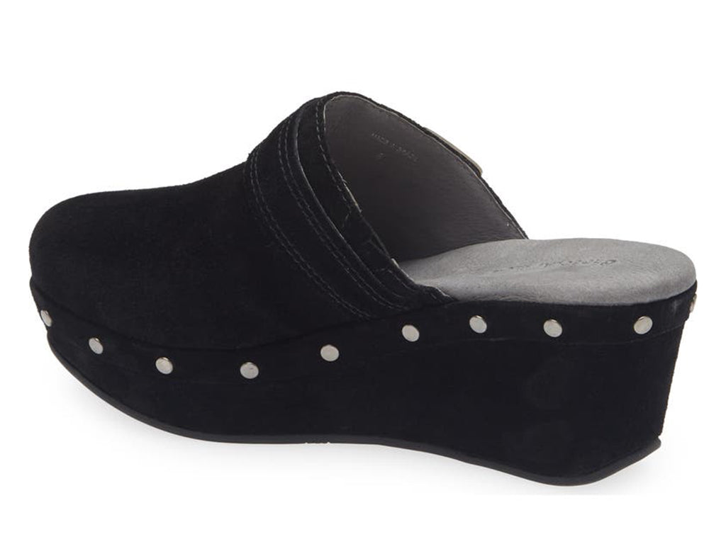 Black suede slide in clog wedge platform shoe with top strap and buckle decoration and grommet studs on a white background side angle view
