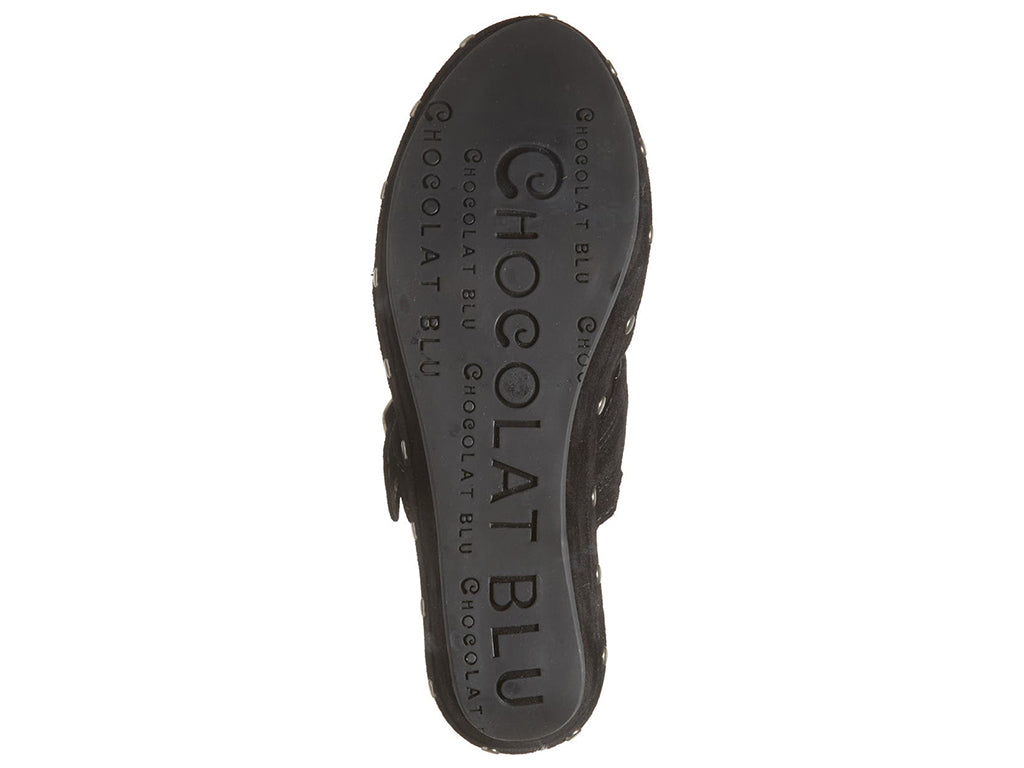 Black suede slide in clog wedge platform shoe with top strap and buckle decoration and grommet studs on a white background bottom sole view