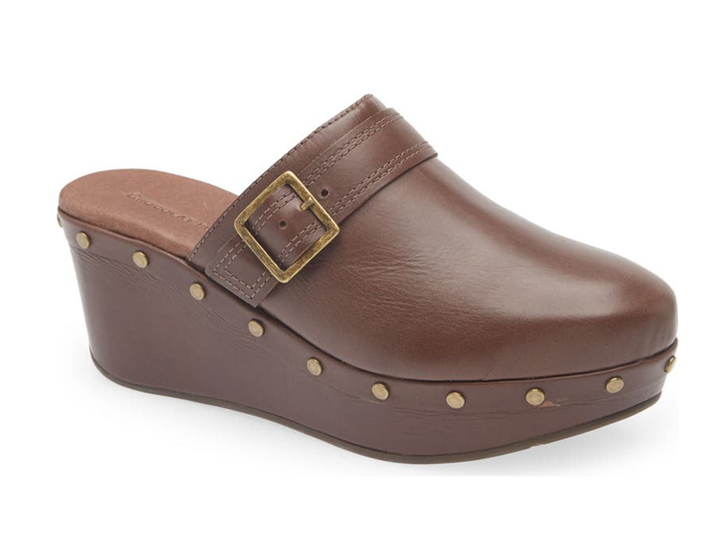 Brown leather slide in clog wedge platform shoe with top strap and buckle decoration and grommet studs on a white background side angle view