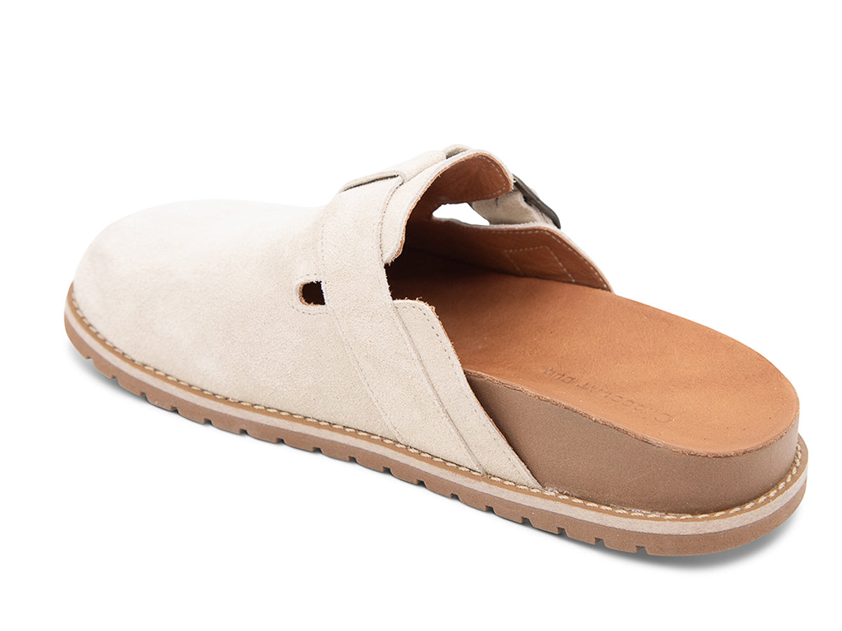 Beige slip-on shoe with a brown sole, strap and buckle on a white background side angle view