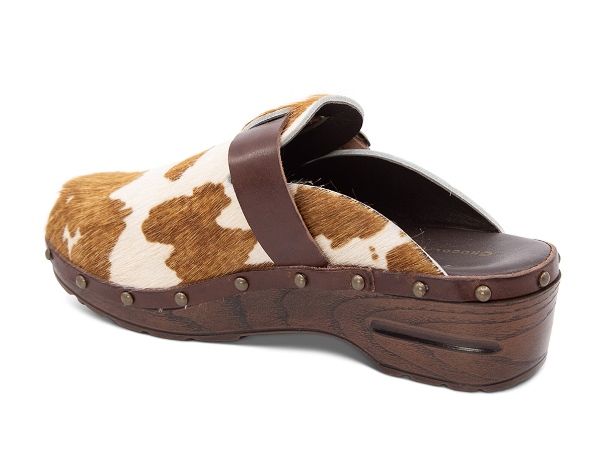 Calf hair clog with brown and white pattern, brown strap and gold buckle on a white background side angled view