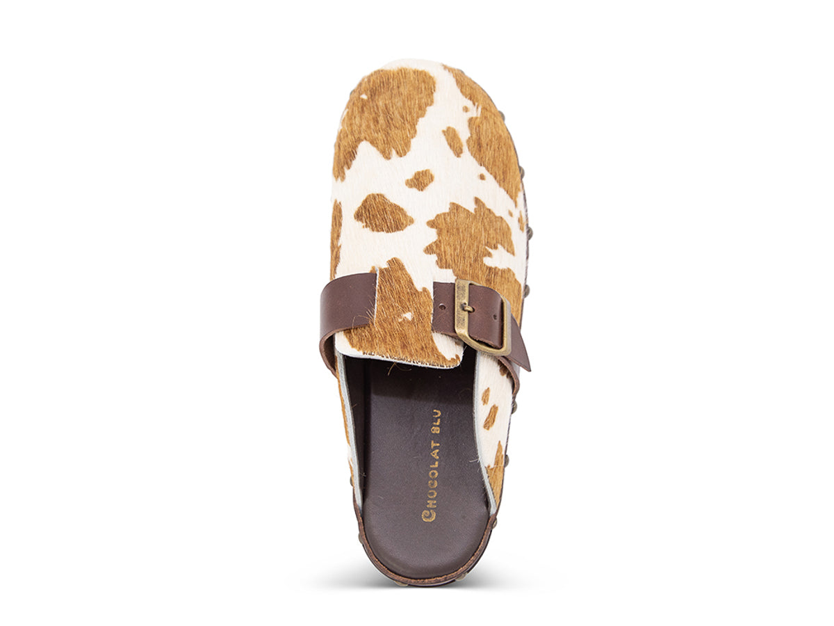 Calf hair clog with brown and white pattern, brown strap and gold buckle on a white background top view