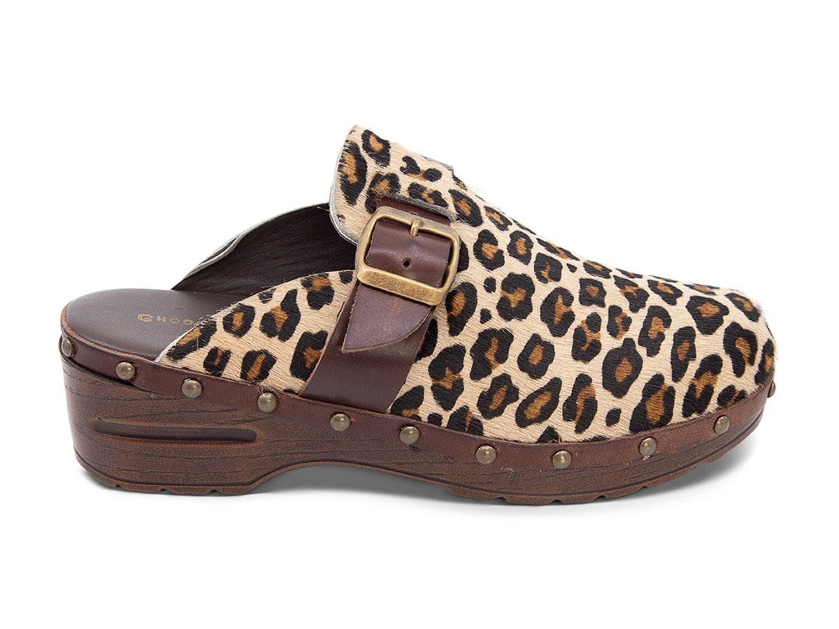 Leopard skin clog with brown and black cow print, brown strap and gold buckle on a white background side view